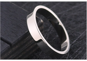 Detailed close-up of a minimalist polished titanium steel ring on dark wood display