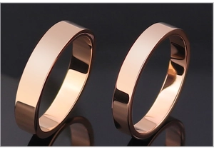 Detailed macro view of polished rose gold couple rings on a sleek black reflective background