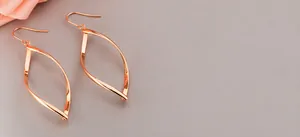 Détail macro de boucles d'oreilles feuilles géométriques en acier titane poli rose doré