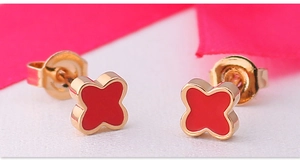 Macro shot of gold four-leaf clover earrings with red enamel and matching butterfly backs