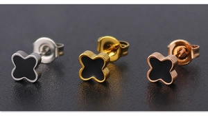 Macro shot of silver gold and rose gold four-leaf clover stud earrings with black inlay