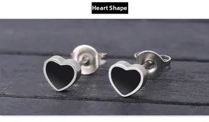 Macro shot of heart-shaped silver earrings with black enamel center on dark wood