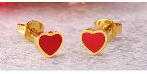 Macro shot of gold-plated heart stud earrings with vibrant red enamel finish