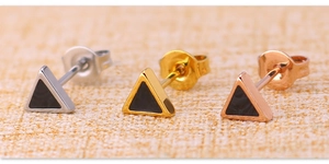 Macro detail of triangular titanium steel studs in silver, gold, and rose gold with black inlay