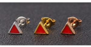 Close-up of geometric triangle earrings in silver, gold, and rose gold with red enamel inlay