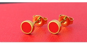 Macro detail of round titanium steel stud earrings with red enamel and golden finish