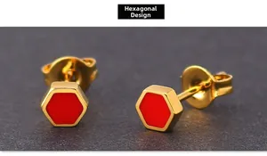 Detail view of gold titanium steel stud earrings with red hexagon enamel inlay