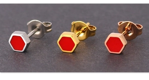 Macro detail of hexagonal stud earrings in silver gold and rose gold with red enamel