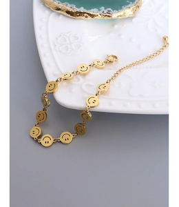 Detail of a minimalist gold-plated smiley face link bracelet with lobster clasp and chain