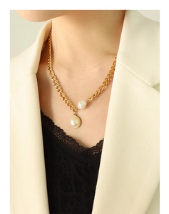 Detailed view of chunky gold chain necklace with baroque pearl and round pendant on model