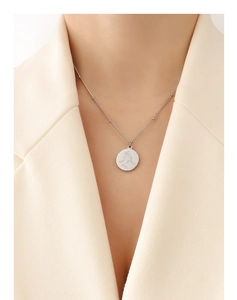 Vue détaillée du collier minimaliste avec gravure de portrait abstrait sur pendentif rond argenté