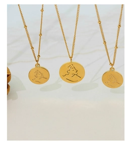 Vue détaillée de trois colliers en pièces d'or minimalistes avec gravures de portraits abstraits