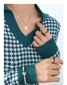 Modella con collana rosa dorata, anelli con pietre nere e set di bracciali di perle