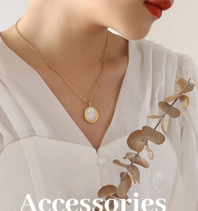 Détail d'un collier avec pendentif ovale en coquillage blanc et chaîne plaquée or