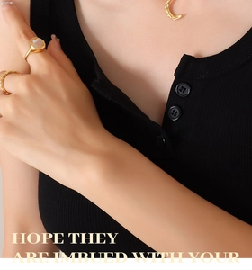 Close-up of gold moon pendant and pearl necklace with square stone ring on a model