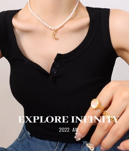 Detail view of freshwater pearl necklace with moon pendant and gold rings on model