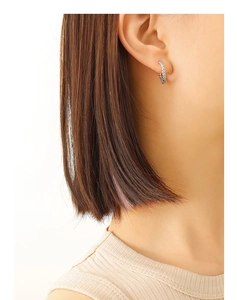 Gros plan sur les boucles d'oreilles créoles argentées avec motif torsadé en spirale