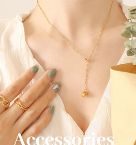 Close-up of gold-plated Y-necklace with hammer-textured ball pendant and rings