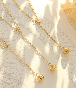 Detailed macro view of the gold-plated geometric sphere pendant and textured link chain