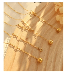 Detail of gold geometric sphere pendant necklace with paperclip chain on wooden surface