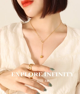 Close-up of gold plated stainless steel ball pendant necklace and stackable rings for women