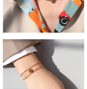 Détail de la gourmette dorée à double couche et du collier avec pendentif Lucky gravé