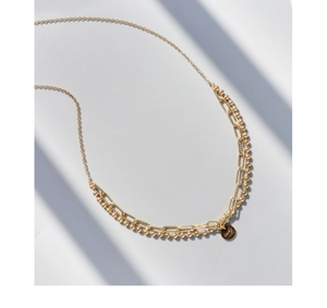 Détail du collier double couche doré avec pendentif Lucky gravé sur une chaîne à billes