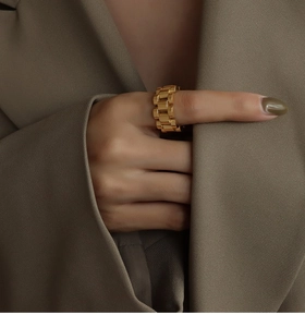 Close-up of a chunky golden watch-strap style titanium steel ring on a model