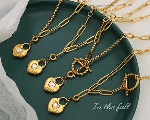 Détail du collier chaîne dorée avec pendentif coeur en opale posé sur un plateau élégant