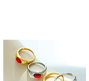Macro shot of stacked gold and silver rings featuring oval red gemstone and textured band