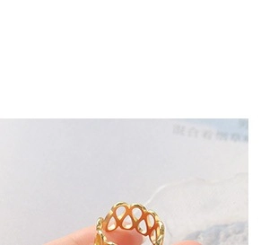 Macro shot of gold-plated hollow lace ring with elegant wave pattern held by fingers