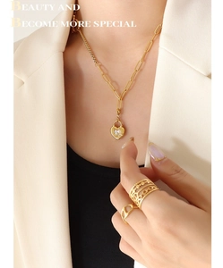 Détail du collier chaîne doré avec cadenas coeur et bagues portés par un mannequin
