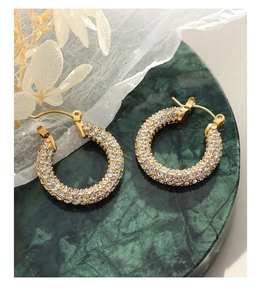 Close-up of gold U-shaped hoop earrings with pavé crystals on dark marble surface
