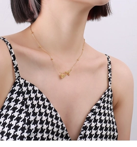 Detailansicht einer goldenen Rosenhalskette mit Perlenkette an einem eleganten Modell