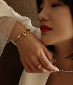 Détail d'un bracelet doré avec pendentif coeur et chaîne à maillons trombone sur mannequin