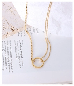 Detail einer doppelten Goldkette mit Ringanhänger auf künstlerischem Papierhintergrund