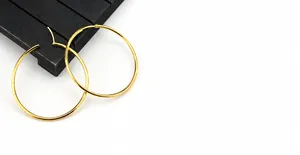 Detail of vacuum plated gold hoop earrings showing the high-polished smooth surface finish