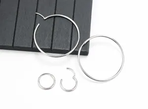 Detailed view of silver hoop earrings and small huggie hoops on a dark wood surface