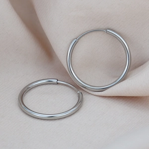 Minimalist silver round hoop earrings on beige silk fabric with polished metal finish