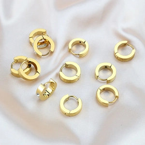 Pendientes huggie dorados pulidos y mate sobre una elegante tela de seda color beige
