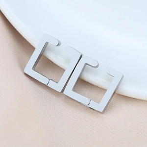 Macro view of polished silver geometric U-shaped ear clips on a white ceramic plate