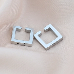 Polished silver U-shaped geometric clip-on earrings on silk fabric background