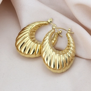 Vue macro de boucles d'oreilles croissant dorées avec rayures sur de la soie