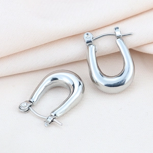 Macro di orecchini a cerchio a U in argento lucido su tessuto a maglia beige chiaro
