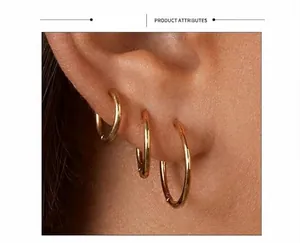 Close-up of three polished gold titanium steel hoop earrings of different sizes on model