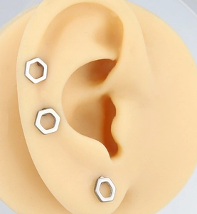 Close-up of geometric hollow hexagon stainless steel stud earrings on a model ear