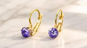 Dettaglio di orecchini dorati con zircone viola rotondo e chiusura a monachella sicura