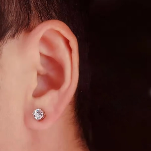 Gros plan d'un clou d'oreille en acier argenté avec zircone ronde portée sur le lobe