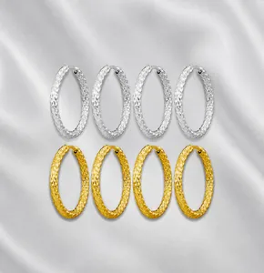 Detail van grote oorringen met gehamerde metaaltextuur in goud en zilver afwerkingen