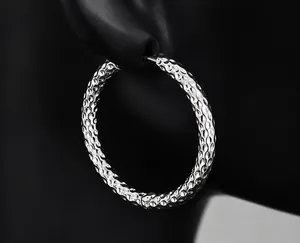 Macro-opname van zilveren titanium stalen creolen met gehamerde textuur op een oormodel